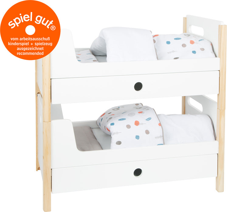 Das Puppenhochbett „Little Button“ besteht aus zwei übereinander gestapelten weißen Spielzeug-Etagenbetten mit Bettzeug, die neben einem runden orangefarbenen „spiel gut“-Siegel präsentiert werden.