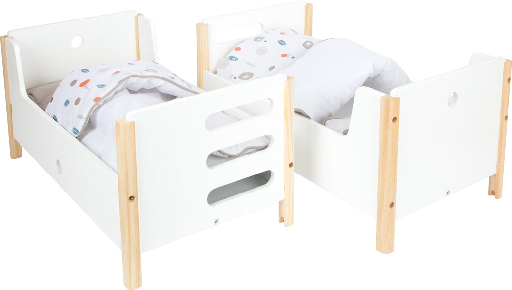 Zwei kleine weiße Holzbetten mit hellen Holzbeinen, jeweils mit gepunkteter Bettwäsche und Kissen: Puppenhochbett „Little Button“.