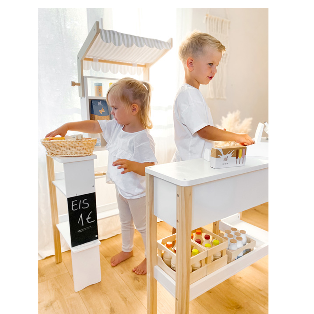 Zwei Kinder spielen mit dem Brotkorb-Set „frisch“ Marktstand und Kasse in einem hellen, sonnendurchfluteten Raum Einkaufen.