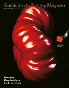 Eine große, glänzend rote Tomate mit einem kleinen roten Gemüsewürfel auf einer Gabel vor einem schwarzen Hintergrund.