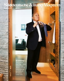 Ein Mann im Anzug steht vor einem offenen Kleiderschrank und rückt seine Krawatte zurecht, Titelbild Süddeutsche Zeitung Magazin.