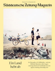 Ein Mann und eine Frau stehen an einem Strand mit einem Fahrrad, Müll und Bergen im Hintergrund; Titelbild einer deutschen Zeitschrift.