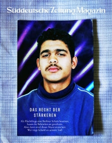 Ein junger Mann mit Schnurrbart posiert vor einem Hintergrund mit neonvioletten Linien und überlagertem Zeitschriftentext.