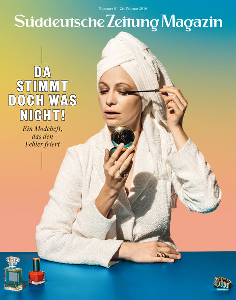 Frau in weißem Bademantel und Handtuch trägt Make-up auf und hält einen Spiegel, auf einem bunten Zeitschriftencover mit deutschem Text.