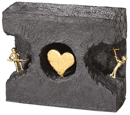 Zwei goldene Figuren graben sich durch einen schwarzen Block zu einem goldenen Herzen in der Mitte.