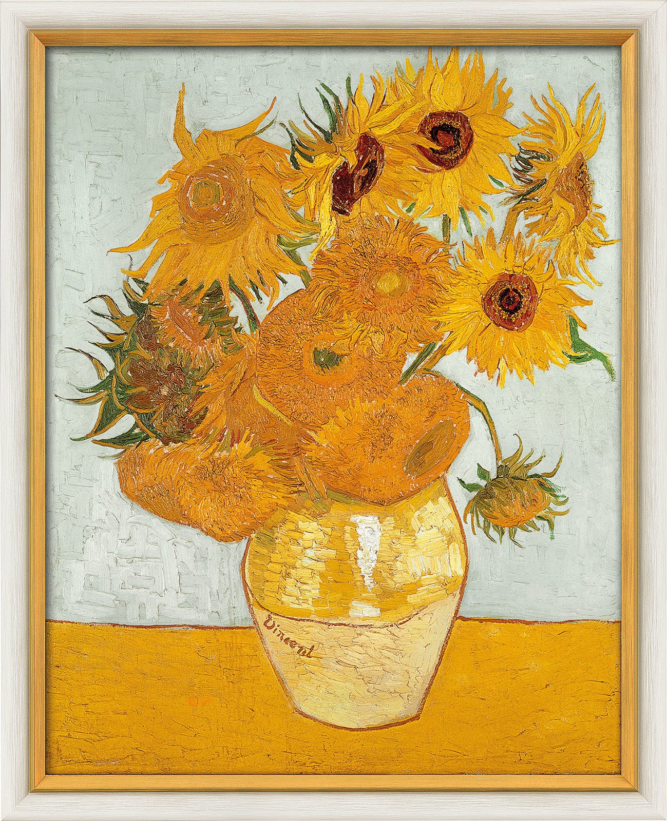 Ein Bild von einer gelben Vase mit Sonnenblumen in Gelbtönen, vor einem hellblauen Hintergrund in einem Holzrahmen.