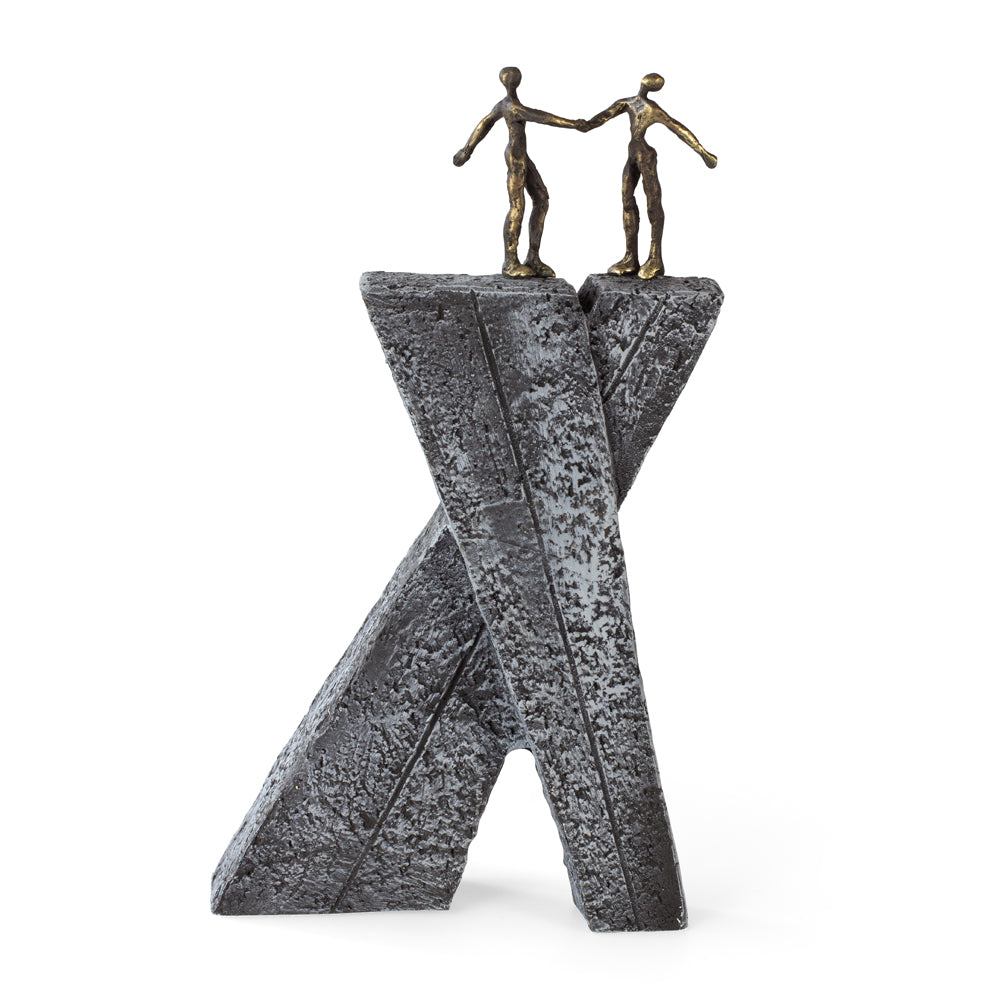 Zwei menschliche Figuren aus Bronze stehen auf sich kreuzenden, strukturierten, grauen, steinartigen Strukturen und bilden ein abstraktes X.