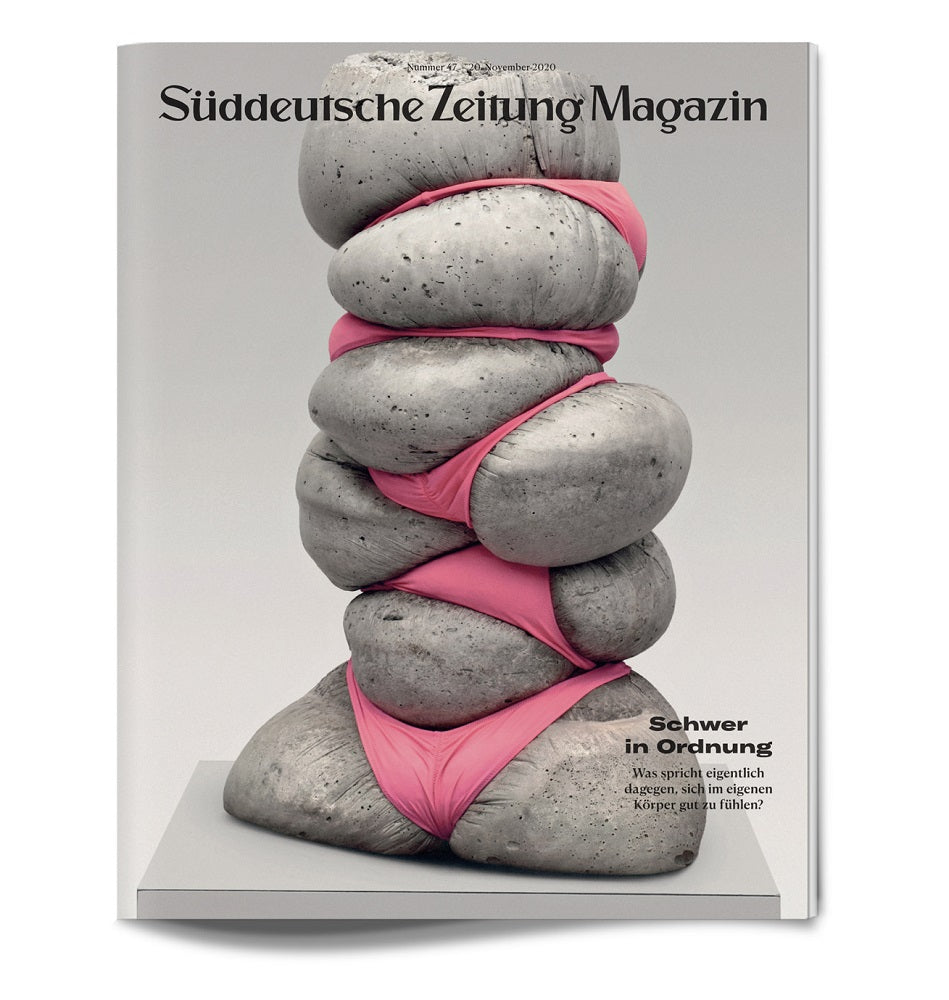 Das Titelbild des Magazins zeigt gestapelte Betonsteine, die fest mit rosa Stoff umwickelt sind.