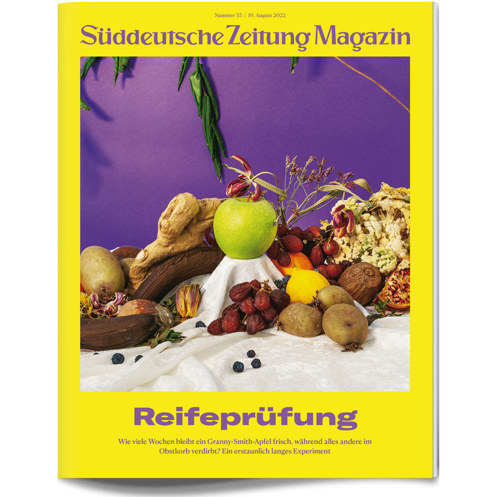 Ein Granny-Smith-Apfel zwischen getrockneten, verfaulten Früchten auf einem bunten Zeitschriftencover mit gelben Rändern.