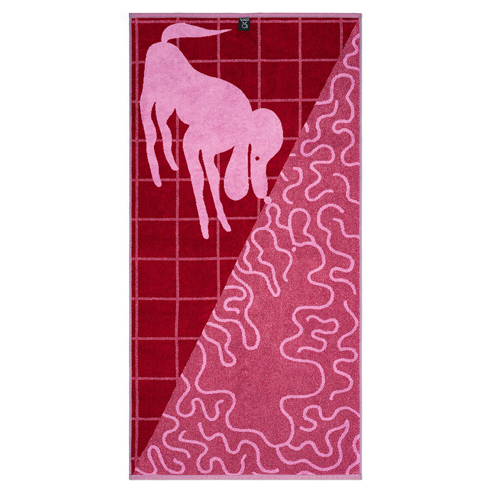Ein rosa Handtuch mit einem Hundemotiv auf rot kariertem Hintergrund und abstrakten rosa Wellenlinien.