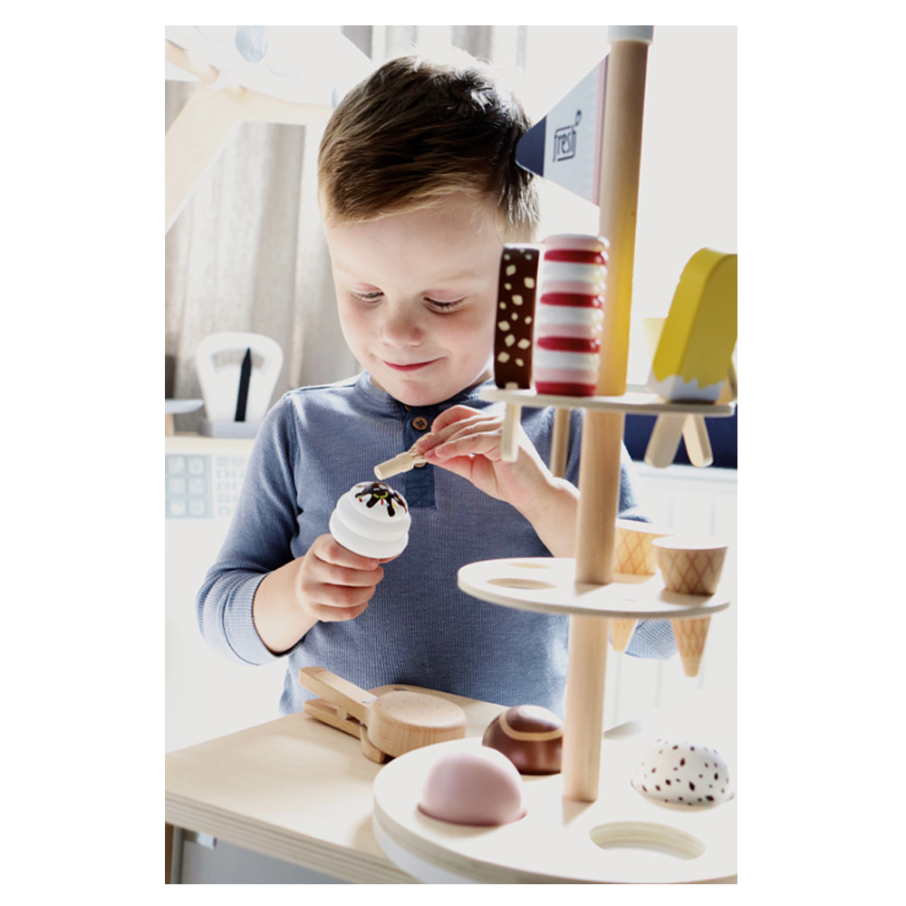 Ein kleiner Junge im blauen Hemd lächelt und spielt drinnen mit dem Eisständer „Fresh“-Spielzeug-Eisset, wobei der Fokus auf fantasievollem Spaß liegt.
