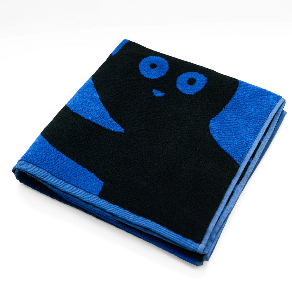 Ein gefaltetes blau-schwarzes Handtuch mit einer verspielten Cartoonfigur mit großen Augen und einem Lächeln.