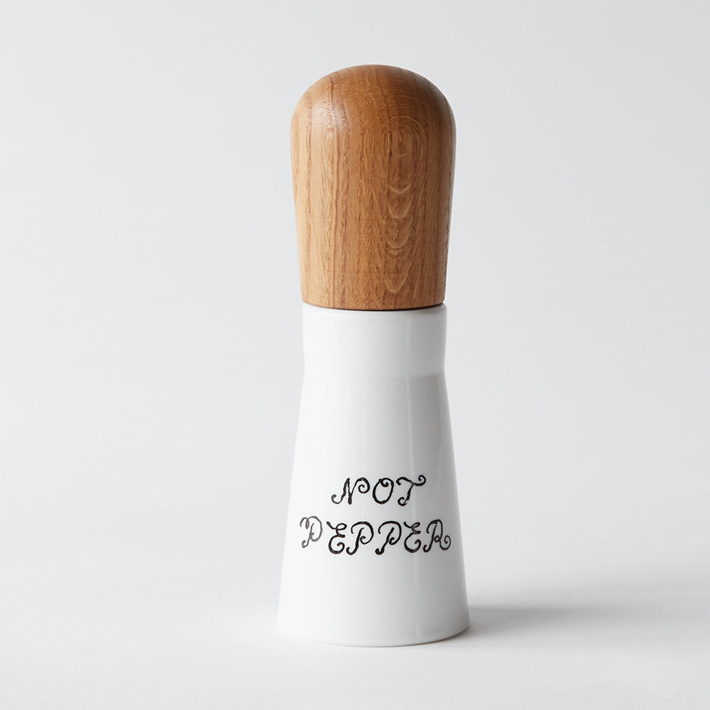Eine weiße Mühle aus dem Gewürzmühlen-Set „Not Salt, Not Pepper“ mit einem Holzdeckel und dem Schriftzug NOT PEPPER in dekorativer Schrift auf der Vorderseite.