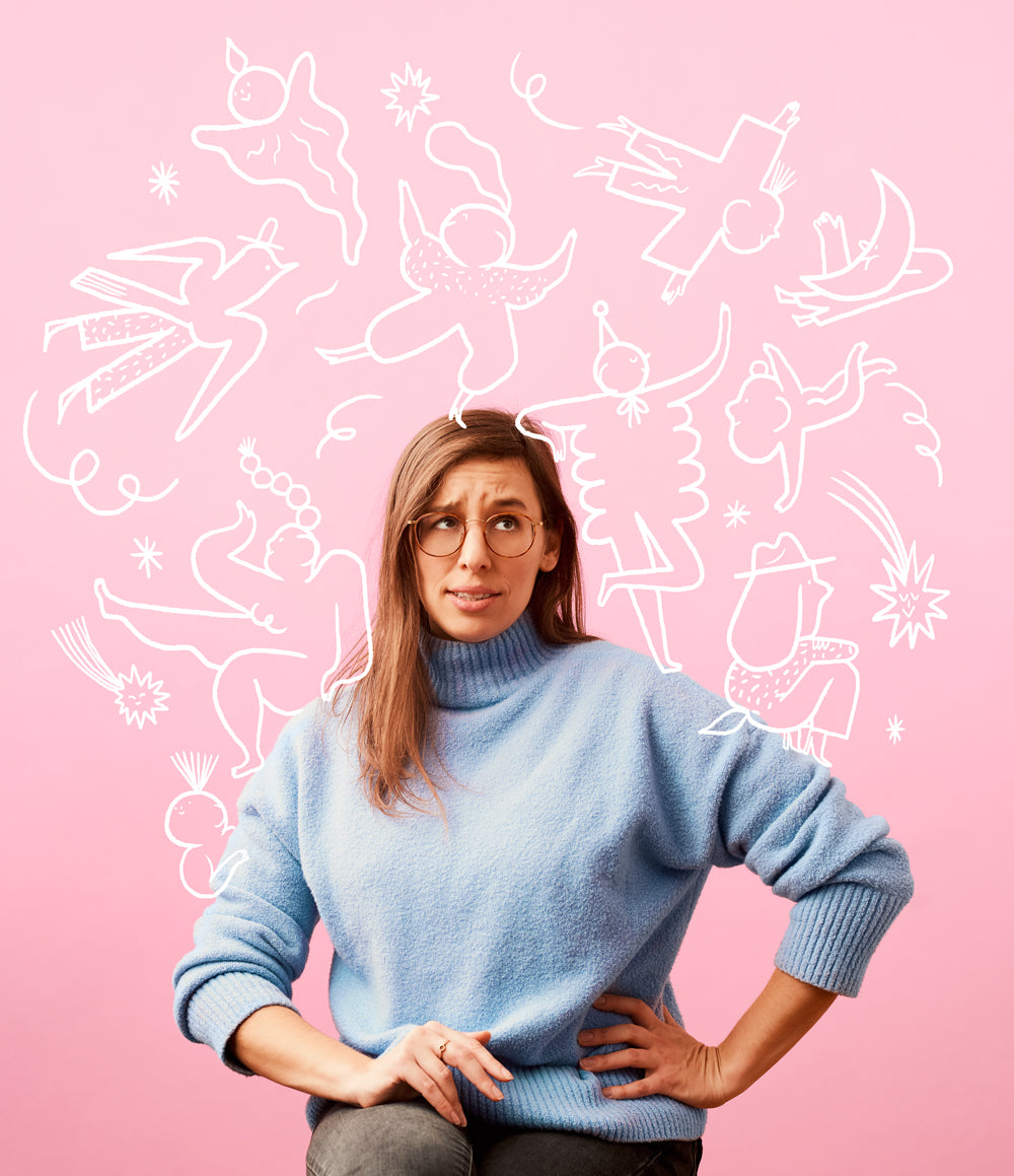 Eine Frau mit Brille sitzt vor einem rosa Hintergrund mit skurrilen weißen Strichzeichnungen um ihren Kopf.