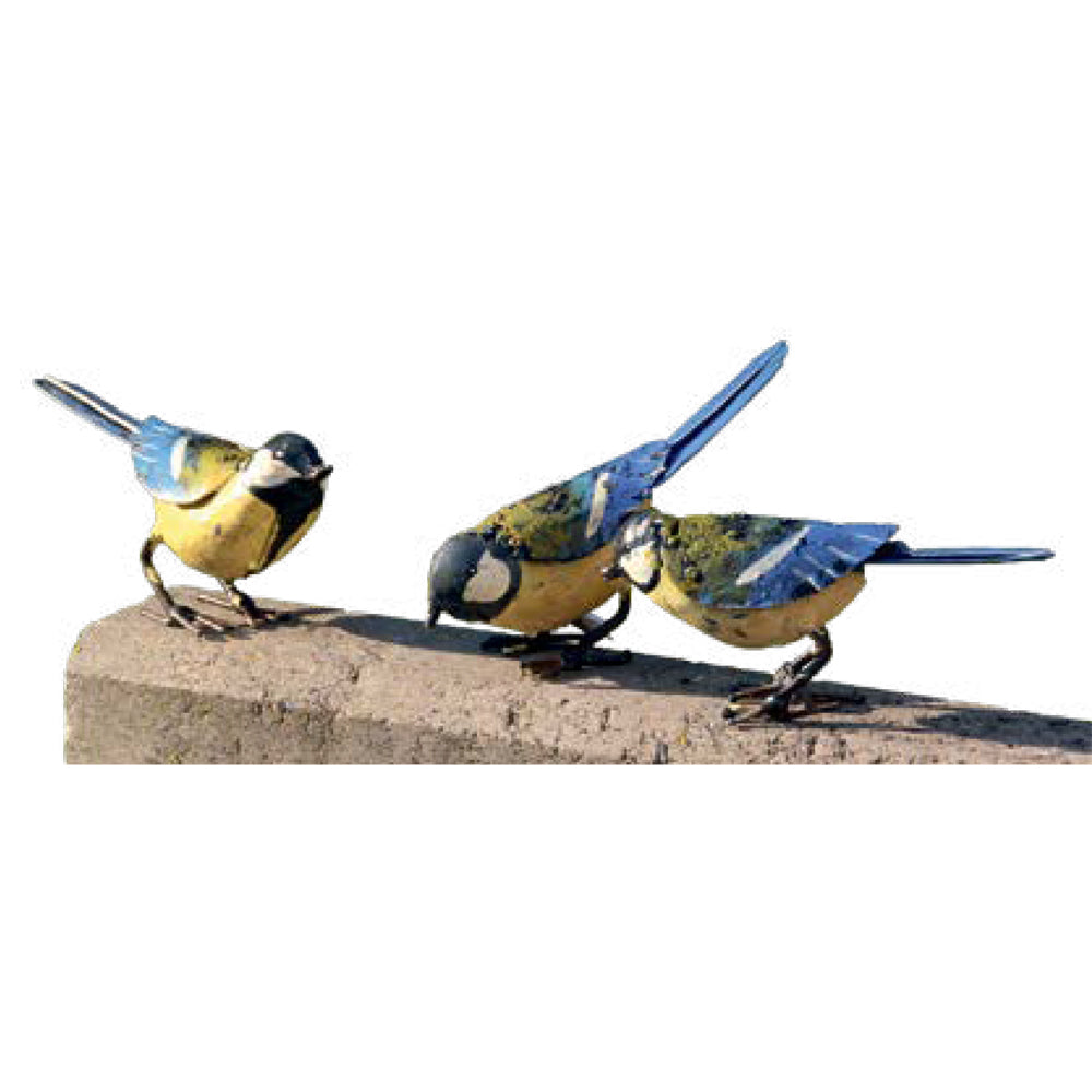 Drei farbenfrohe Vogelskulpturen aus Metall mit blauen Flügeln sitzen auf einer rauen Steinoberfläche vor einem weißen Hintergrund.
