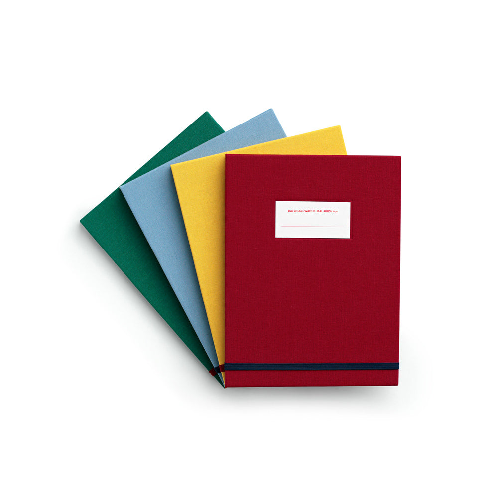 Vier geschlossene Notizbücher mit grünem, blauem, gelbem und rotem Einband, aufgefächert auf weißem Hintergrund.