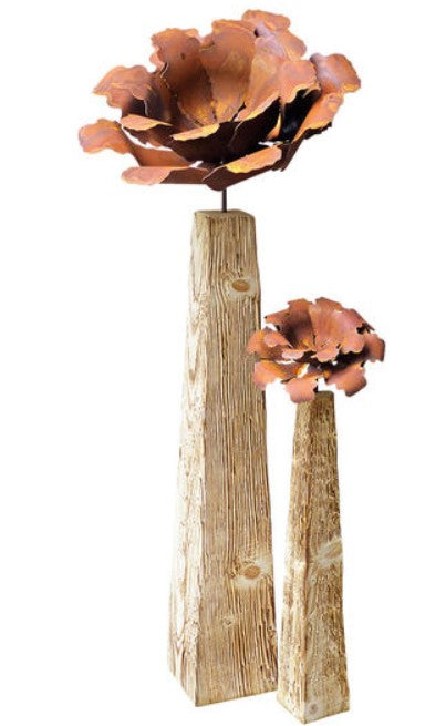 Zwei hohe Holzständer, gekrönt von großen, blumenförmigen Metallskulpturen in Kupfertönen.