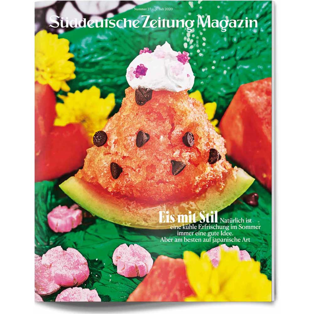 Ein Dessert in Form einer Wassermelonenscheibe mit Schokoladensplittern, Schlagsahne und bunten essbaren Blumen.