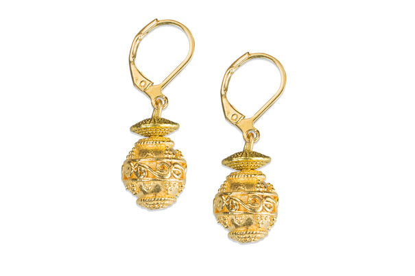 Ein Paar verzierte goldene Tropfenohrringe mit komplizierten Mustern und Klappverschlüssen auf weißem Hintergrund.