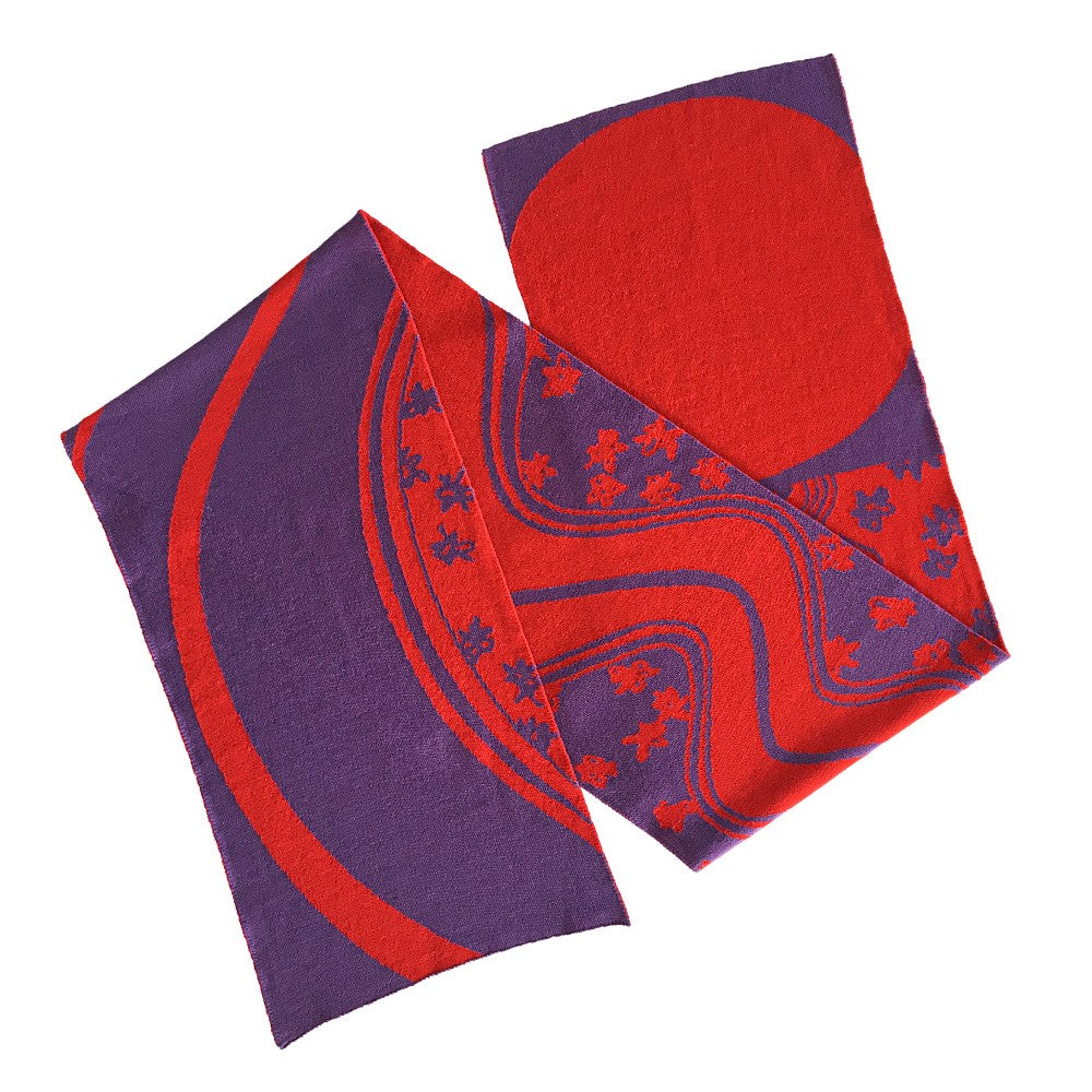 Ein lila Schal mit roten abstrakten Linien, einem großen roten Kreis und kleinen Blumenmustern.