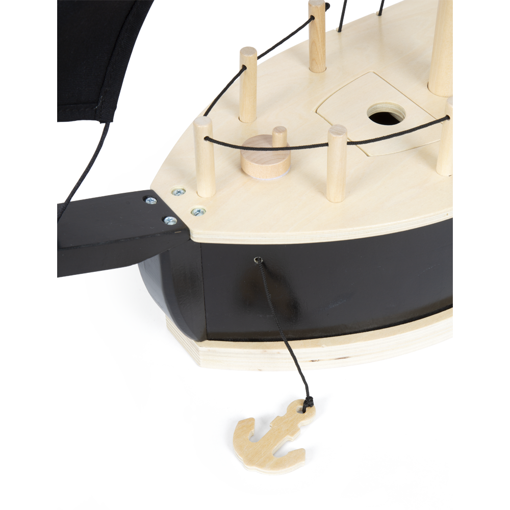Das Piratenschiff ist ein hölzernes Spielzeugboot mit einem schwarzen Rumpf, Deckspfosten, einer Schnur und einem über der Seite hängenden Holzanker.