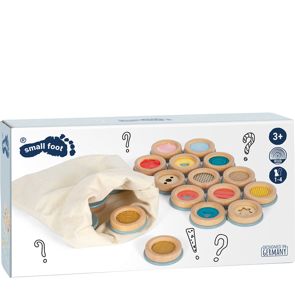 Fühlmemo „Sensory“: Box mit Stoffbeutel und Holz-Memory-Scheiben in verschiedenen Farben und Mustern, geeignet für Kinder ab 3 Jahren.