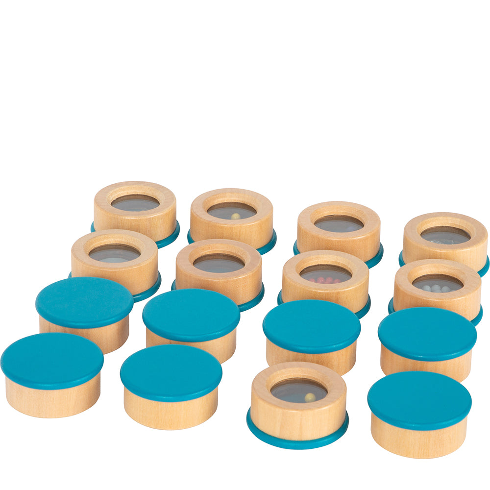 Das Hörmemo-Set „Sensory“ enthält passende Spielsteine aus Holz mit blauen Deckeln. Bei einigen Deckeln kommen Perlen und Muster im Inneren zum Vorschein.