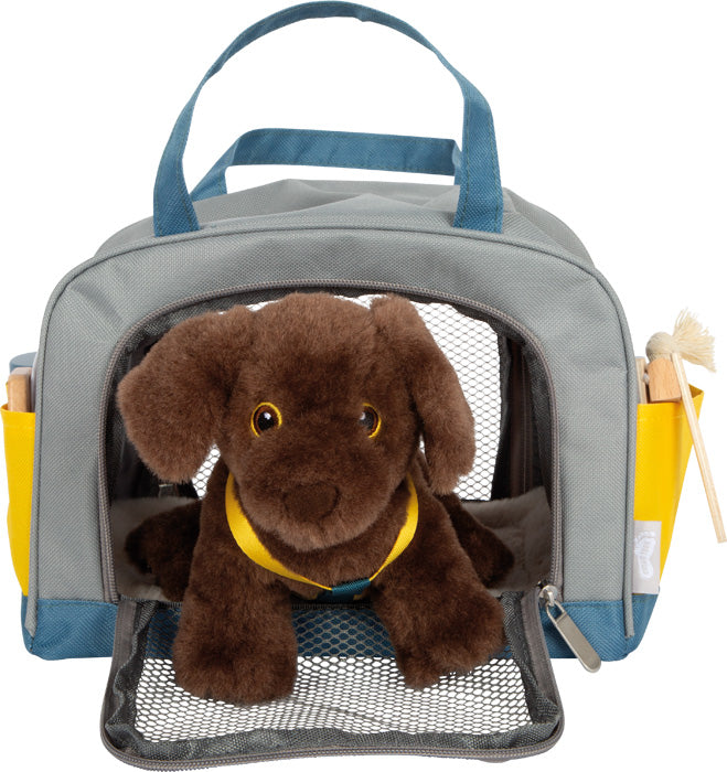 Ein brauner Plüschhund wird in einer grau-blauen Tragetasche mit Netztür geliefert, dazu Spielzeug-Pflegeutensilien. Produkt: Hund mit Tasche und Pflege-Set.