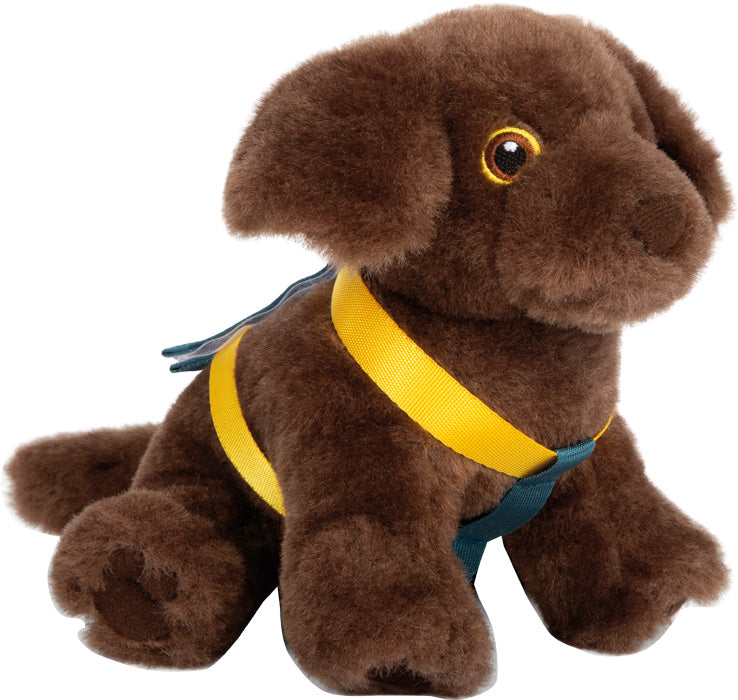 Das Hund mit Tasche und Pflege-Set ist ein aufrecht sitzendes braunes Plüschhundespielzeug, das mit einem gelb-blauen Geschirr bekleidet ist.
