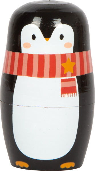 Eine niedliche Nistpuppe, die als Pinguin bemalt ist und einen roten Schal mit einem gelben Stern trägt.