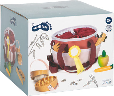 Schachtel mit einem Pflegeset für Kinder mit Spielzeugbürsten, Kamm, Apfel und Band, empfohlen für Kinder ab 3 Jahren.