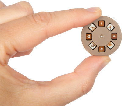 Eine Hand hält eine kleine, rundes Projektionsscheibe, die mit verschiedenen Symbolen versehen ist.