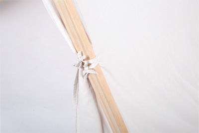 Nahaufnahme einer hölzernen Zeltstange, die mit weißem Stoff vor einem schlichten weißen Hintergrund zusammengebunden ist.