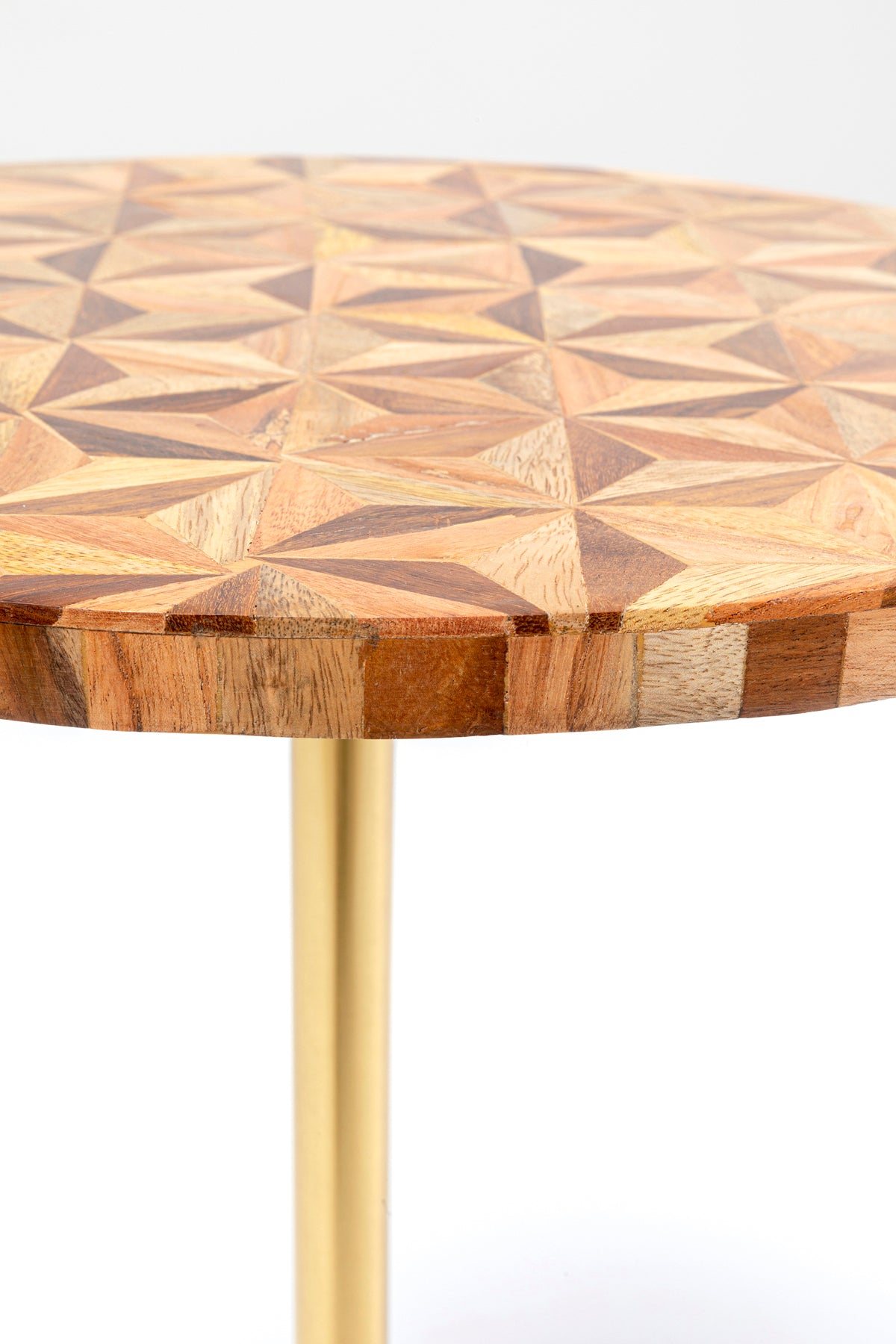 Eine Nahaufnahme des Beistelltischs Domero Geo Braun Ø40cm zeigt seine runde Holzplatte mit einem mehrfarbigen geometrischen Parkettmuster und einem einzelnen schlanken, messingbeschichteten Metallbein.