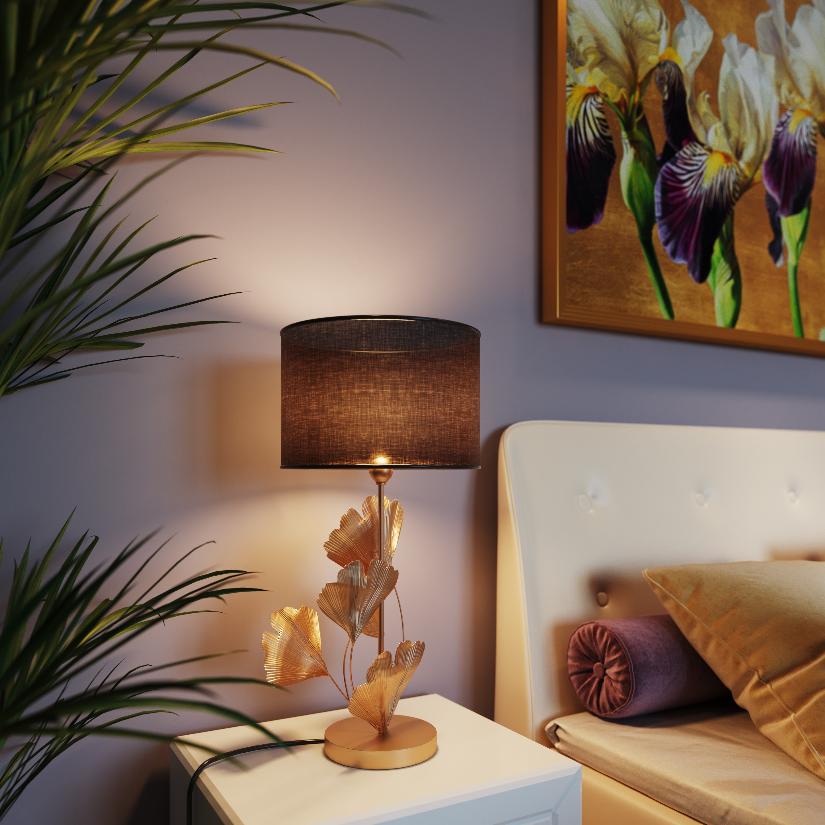 Die Tischleuchte Flores Gold mit schwarzem Schirm und goldenem Ginkgoblatt-Design steht auf einem weißen Nachttisch neben einem cremefarbenen Bett mit Polsterknöpfen, während ein Pflanzen- und Blumengemälde dem gemütlichen Zimmer schickes asiatisches Flair verleiht.