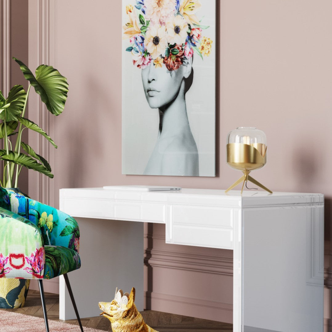 Ein moderner Raum mit weißem Schreibtisch, farbenfrohem Blumenstuhl und goldener Hundestatue. Die Tischleuchte Golden Goblet Ball sorgt für Retro-Charme, während ein Schwarz-Weiß-Porträt einer Frau mit leuchtendem Blumenkranz die Wand schmückt.