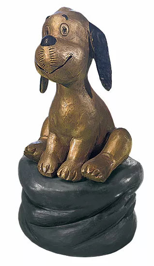 Die Loriot: Skulptur „Wum“, Version in Bronze, zeigt einen lächelnden braunen Cartoon-Hund mit schwarzen Ohren, der auf einem runden schwarzen Sockel sitzt.