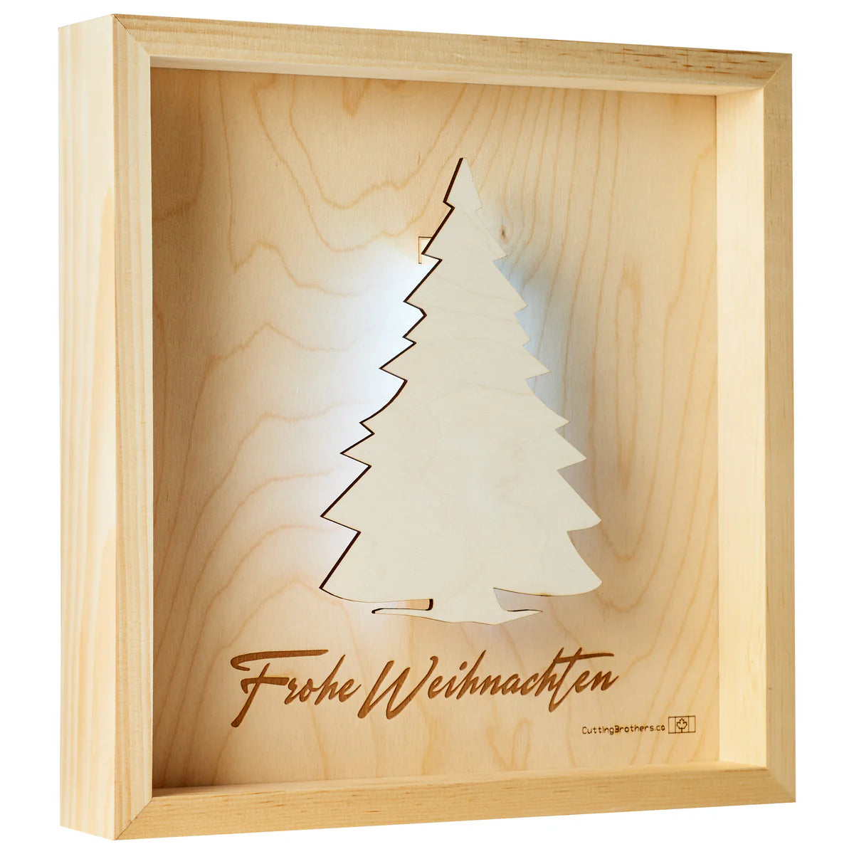 Gerahmtes Kunstwerk aus Holz mit einem ausgeschnittenen Weihnachtsbaum und der Gravur Frohe Weihnachten darunter.