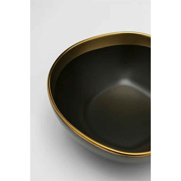 Eine schwarze Schale mit Goldrand, von oben auf weißem Hintergrund fotografiert.