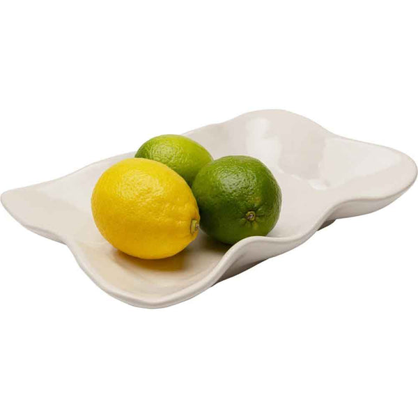 Eine weiße gewellte Schale mit zwei grünen Limetten und einer gelben Zitrone.