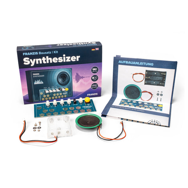 Synthesizer-Bausatz mit Komponenten, Drähten, Handbuch und Schachtel auf einer weißen Fläche.