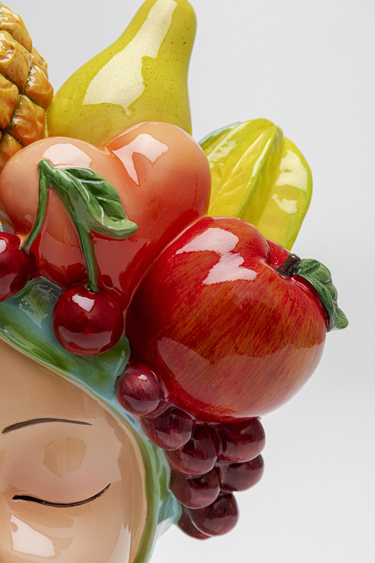 Eine Nahaufnahme der Deko Vase Fruity, einer lebendigen sizilianischen Keramikskulptur mit einem heiteren Gesicht und einem farbenfrohen Fruchtarrangement – perfekt für die Dekoration Ihres Couchtischs.