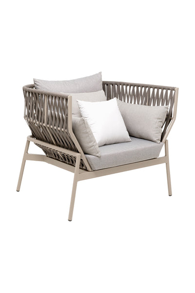 Moderner Sessel mit taupefarbenem Metallgestell, geflochtener Rückenlehne und hellgrauem Sitzkissen, mit drei Plüschkissen in Weiß und Grau.