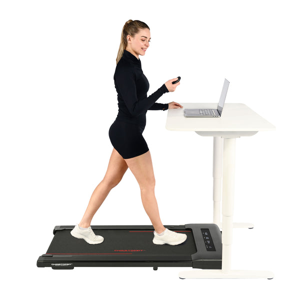 Frau, die auf einem Laufband läuft, während sie an einem Laptop an einem Stehpult arbeitet.