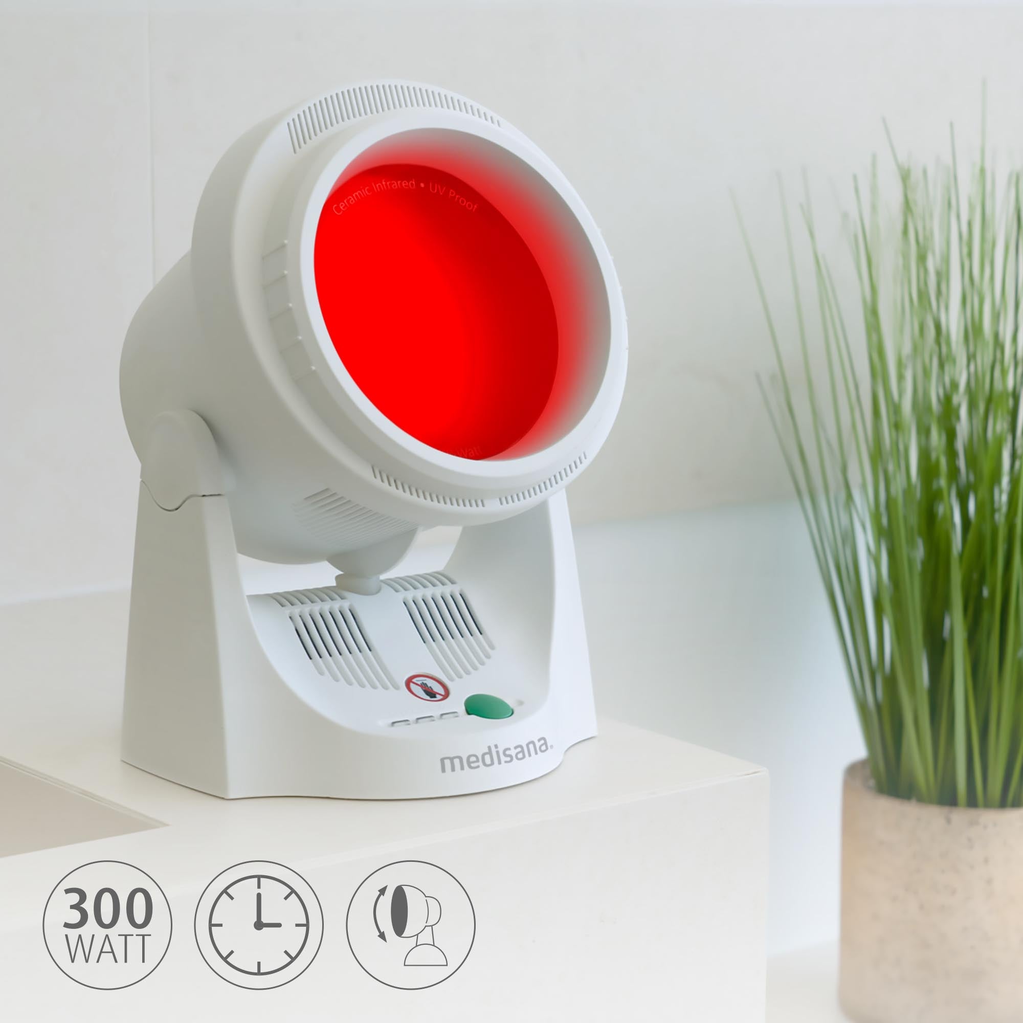 Eine weiße Medisana-Infrarotlampe leuchtet rot auf einer Theke neben einer grünen Topfpflanze. Symbole zeigen eine Leistung von 300 Watt an.