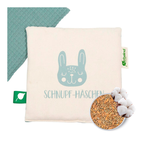 Quadratisches Weizenkissen mit einem niedlichen Hasengesicht, beschriftet mit Schnupf-Häschen und dargestellt mit Körnern und Baumwolle.