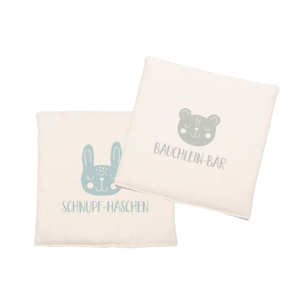 Zwei weiße Stoffblöcke mit Tiergesichtern und deutschem Text: SCHNUPF-HÄSCHEN und BAUCHLEIN-BÄR.