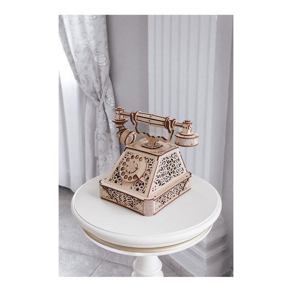 Auf einem runden weißen Tisch in einem hellen, eleganten Raum steht ein hölzernes Drehtelefon im Vintage-Stil.