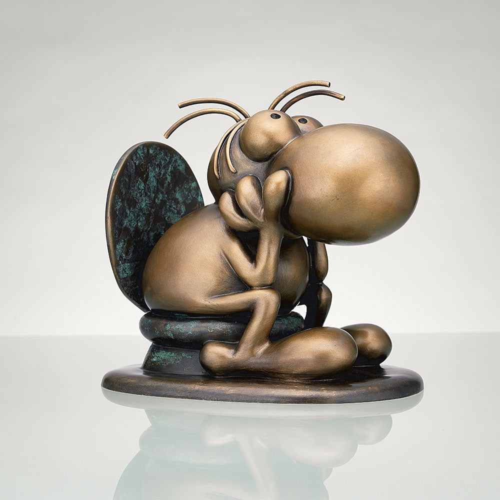 Die Bronzeskulptur „Think“ von Mordillo stellt ein Cartoon-Insekt mit großen Augen und Nase dar, das sitzt und sein Kinn auf seinen Händen ruht.
