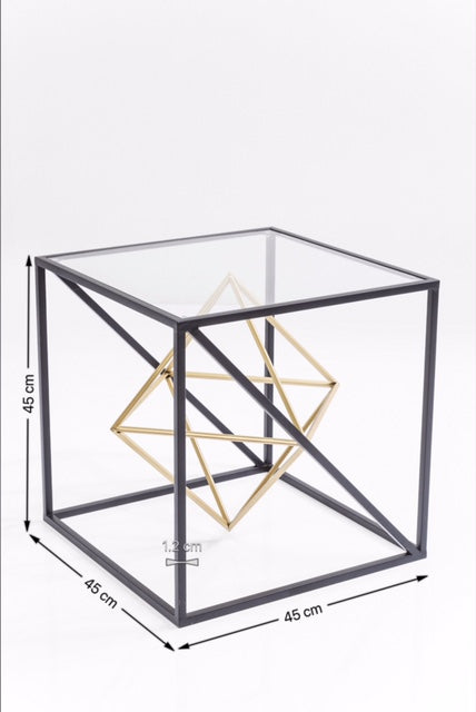 Der Beistelltisch Prisma ist ein moderner, quadratischer Tisch mit Glasplatte, schwarzem Metallrahmen und goldener geometrischer Skulptur im Inneren. Maße: 45 x 45 x 45 cm.